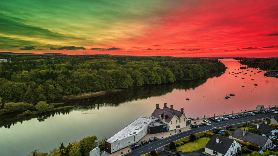 Scenic riverside view at sunset, with vibrant sky and lush forest; perfect for a tranquil getaway at riverside hotel.